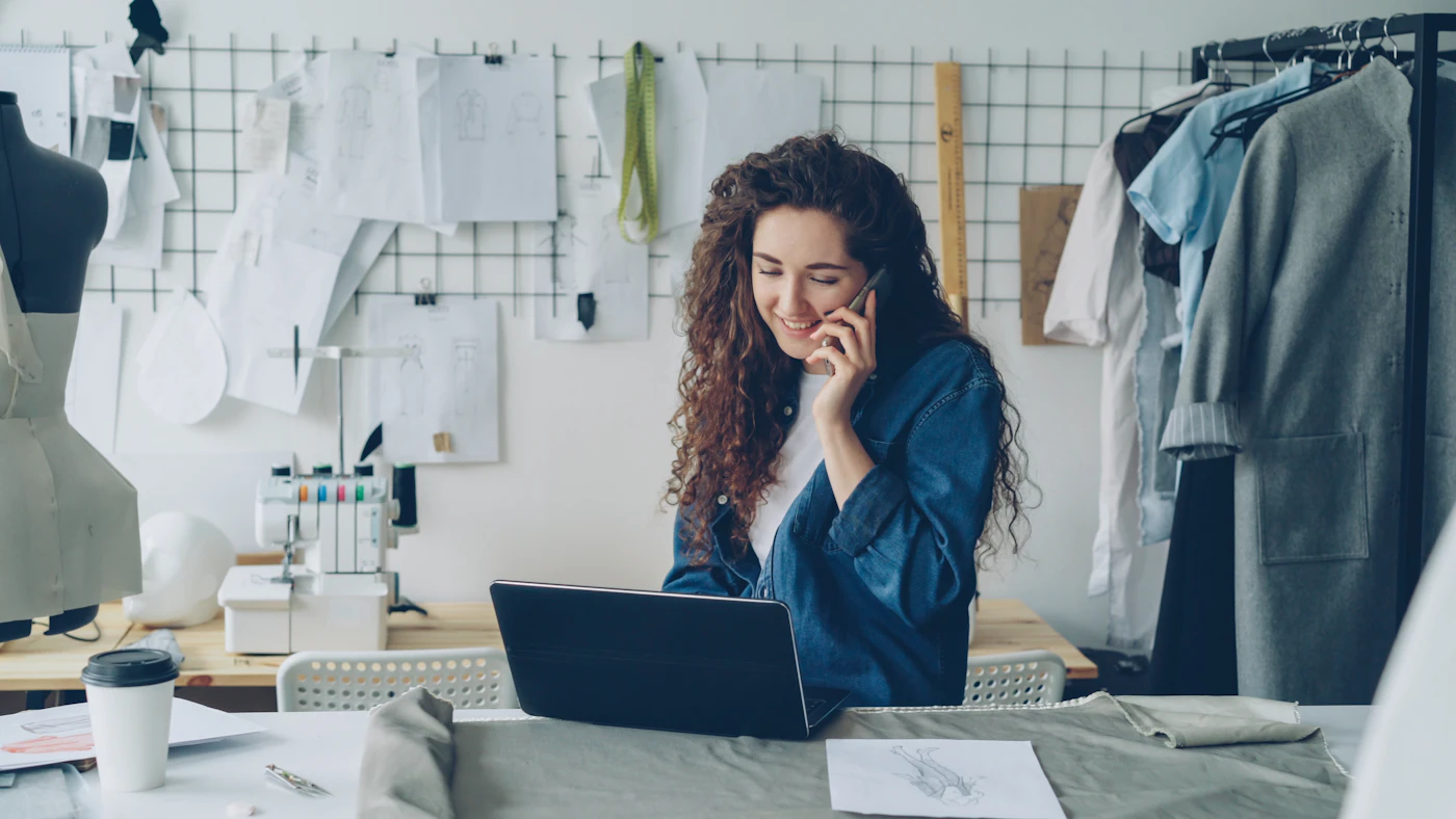 Una stilista freelance al telefono davanti al portatile